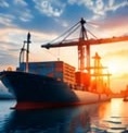 Container ship and port cranes at sunset